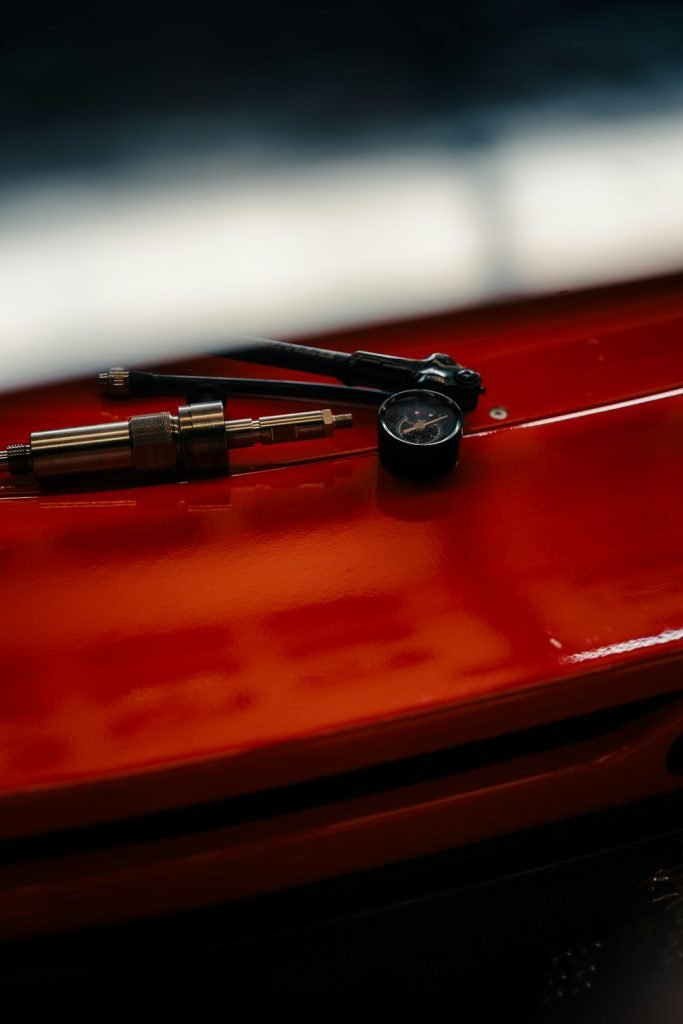 tire-pressure-gauge-and-inflator-on-red-surface-yeg5qqmtqhk